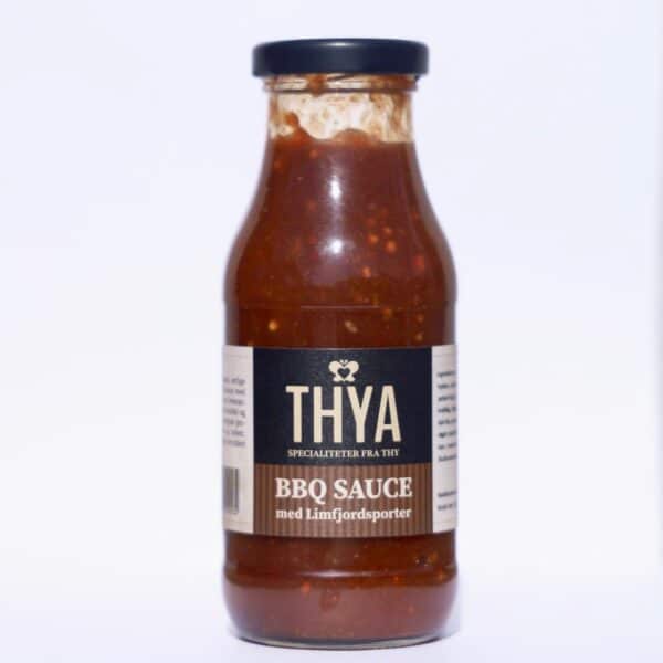 Flaske med Thya BBQ sauce, sort etiket, hvid tekst, sort låg, synlig brun sauce indeni.