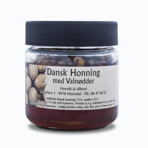 En gennemsigtig glasbeholder med sort låg, mærket "Dansk Honning med Valnødder" og produktinformation.