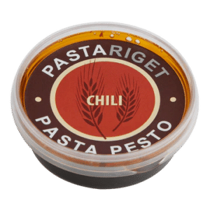 Rund beholder med Pastariget Chili Pesto, rød/hvid/brun etiket med hvede og "Chili" i midten.