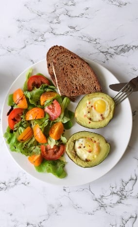 Bagt Avocado med Æg og Salat på hvid tallerken