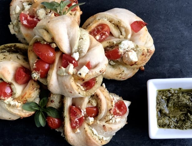 Pesto Twisters med Grøn Pesto, Knust Feta og Tomat på et bord.