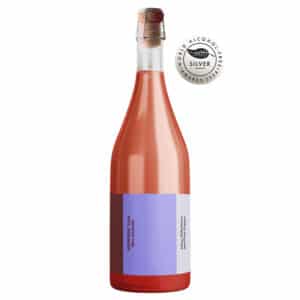 Flaske af ARENSBAK Rosé, alkoholfri, lyserød med korkprop og lilla/hvid etiket.