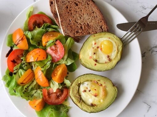 Bagt avocado med æg og salat på en tallerken