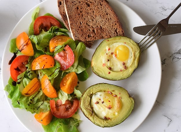 Bagt avocado med æg og salat på en tallerken