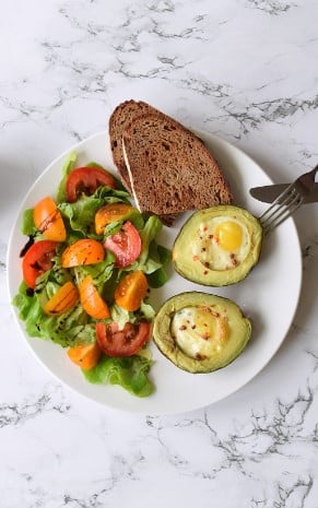 Bagt avocado med æg og salat på en tallerken