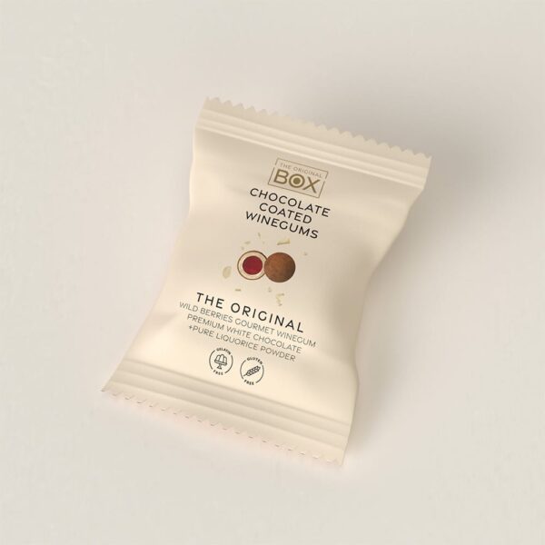 Beige pakke med "BOX The Original", chokoladeovertrukne vingummier med bær og lakridspulver.