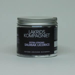 Glaskrukke med sølvlåg, sort label, hvid tekst: "Ekstra stærk salmiak lakrids", fra Lakrids Kompagniet.